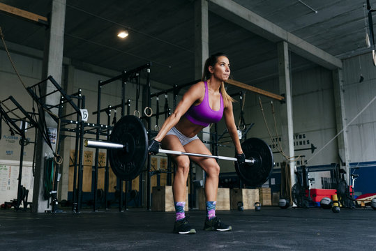 Determined sportswoman lifting heavy barbell
