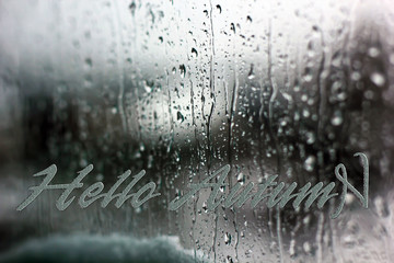 The inscription "Hello Autumn" on a background of a wet window. Raindrops on the window