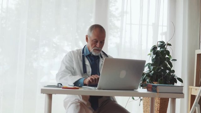 Senior doctor with laptop working at the office desk.