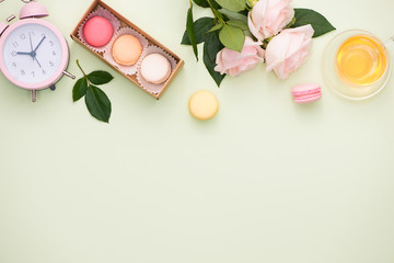 Colorful macaroons and rose flowers with gift box on wooden table. Sweet macarons in gift box. Top view