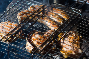 Meat and sausages are fried in a street grill, close-up