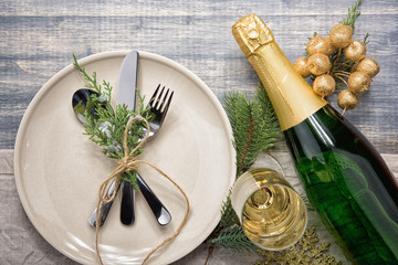 Christmas meal table setting design, flat lay. Empty plate, glass, cutlery, bottle of champagne and...