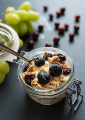yoghurt with grapes, muesli crumble and cranberries in preserving jar