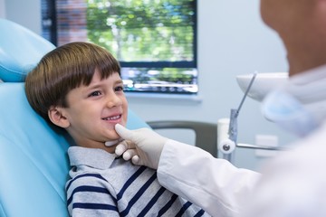 Fototapeta premium Smiling boy looking at dentist while sitting on chair