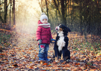 child and dog together in autumn park