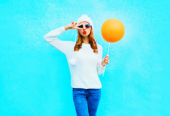 Fashion woman holds orange balloon in white hat on a blue background