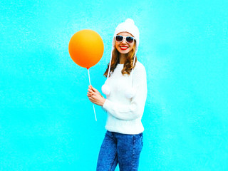 Fashion smiling woman with an air balloon on a blue background