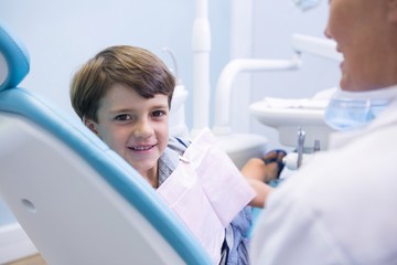 Obraz premium Portrait of cute boy sitting on dentist chair by dentist