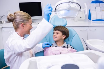 Side view of dentist adjusting electric light while boy sitting