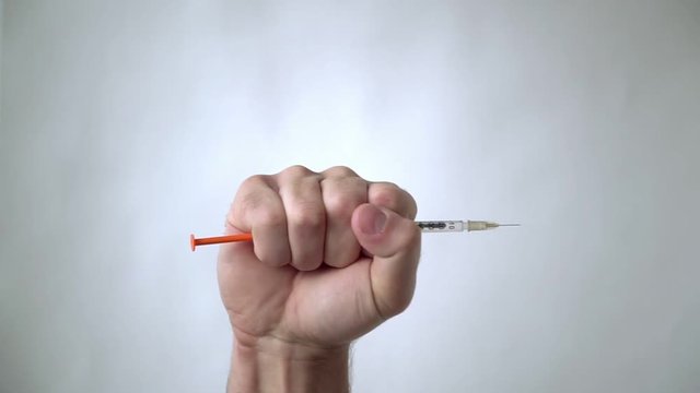 The man's hand holds, and then throws out the syringe. Victory over a disease or drug addiction.