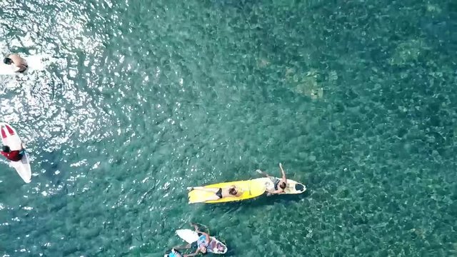 Aerial top view zooming out on surfer girl with instructor