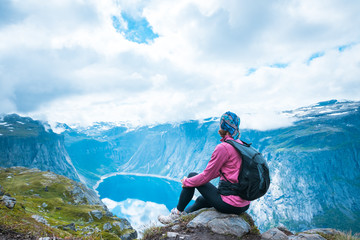 Young woman with backpack on top of fjord Norway