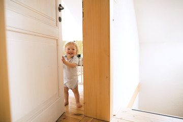 Portrait of happy baby boy opening the door
