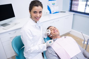 Fototapeta premium Portrait of dentist holding equipment while standing by patient