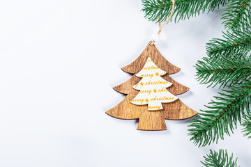 Christmas frame with the branches of the Christmas tree and wooden decorations on white background. Simple Christmas composition with free space