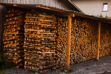 Chopped firewood stacked in a woodpile under a canopy