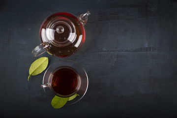 Tea cup with and tea leaf sacking on the wooden table and the tea plantations background