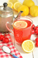 Fruit cherry tea with slice of lemon in mug, old teapot and cherries