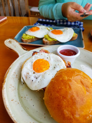 Healthy diet breakfast. Organic avocado toast with fried egg and Veal bacon toast. Woman's hand background. Selective focus. Copy space.