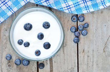 White yogurt in a bowl with blueberries on wooden table