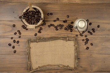 Coffee bean grain ,bottle of milk and sack fabrice board on brown wood table background , include copyspace for add text or graphic in advertise or marketing content