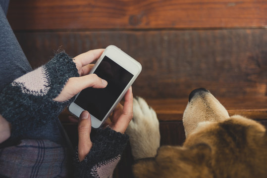 Girl siting next to her dog using phone