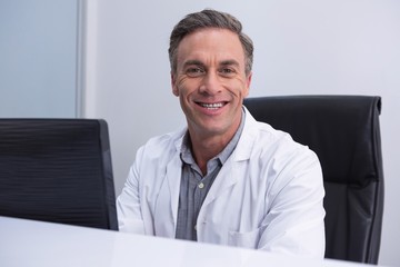 Portrait of dentist sitting by computer at table