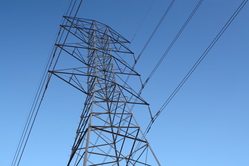 High-power electric distribution tower with a blue sky background