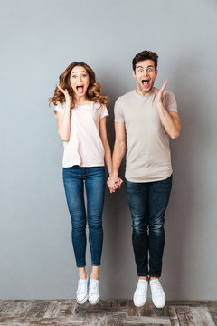 Full length portrait of a cheerful young couple holding hands