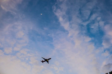 Flying airplane in blue sky with moon