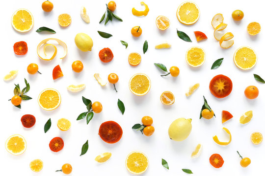 Creative flat layout of fruit, top view. Sliced orange, lemon, persimmon, tangerine, green leaves isolated on white background. Food wallpaper, composition pattern of fresh fruits.