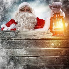 Santa Claus with lamp of light in hand and free space for your text on retro wooden billboard place 