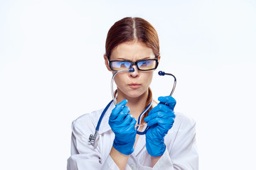 Beautiful young woman in glasses and medical clothes holds a stethoscope on white isolated background, doctor, medicine