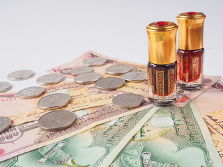 Oil bottle agarwood tree stands on the Arab dirham. Arabian oud attar perfume or agarwood oil fragrances in mini bottle.


