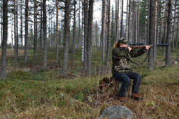 Young female moose hunter aiming