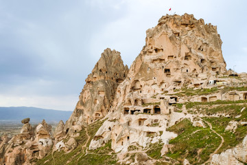 Rock castle in Cappadocia, Turkey. The castle in a mountain under cloudy sky. The castle looks strong and there are many caves can been seen in the castle. 