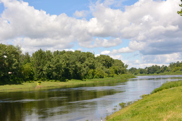 Fototapeta na wymiar beautiful summer fairy tale, a bright summer natural landscape, the Dvina river against a blue sky with white clouds