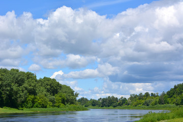 beautiful summer fairy tale, a bright summer natural landscape, the Dvina river against a blue sky with white clouds