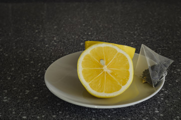 Lemon for tea with a tea bag on a granite table