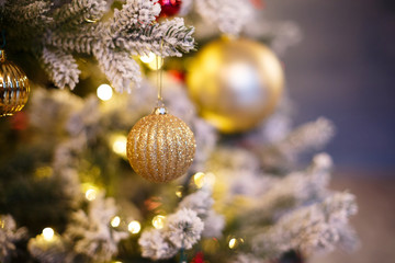 Close-up photo with decorations of christmas tree. Selective focus (Narrow depth of field). Christmas gold balls on a christmas tree branch. New Year's concept