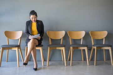 Woman is sitting to review the documents while waiting for a job interview.
