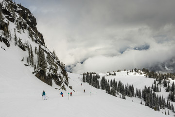Tourists snowboarding and skiing on snow covered mountain, Whistler, British Columbia, Canada