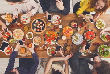 Gadget device addiction, happy people have dinner with smarphones