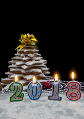 Candles in the form of 2018 new year near homemade gingerbread Christmas tree with decorations on...