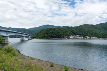 The beauty of the forest mountains above the lake in Japan. Pier on the beach