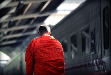 A monk at train station Thailand with sunlight at the side of his face