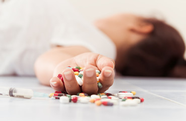 Overdose - close up of pills and addict lying on the floor
