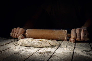 Hands rolling dough in flour