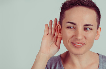 Closeup head shot macro face young nosy woman hand to ear gesture carefully intently secretly...