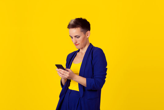 Phone addiction. Interested addicted business woman girl looking to her phone gadget internet isolated yellow background wall.
